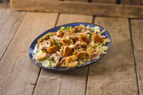 Krokante kip, ijsbergsla, kaas, bacon, rode ui en huisgemaakte ceasardressing